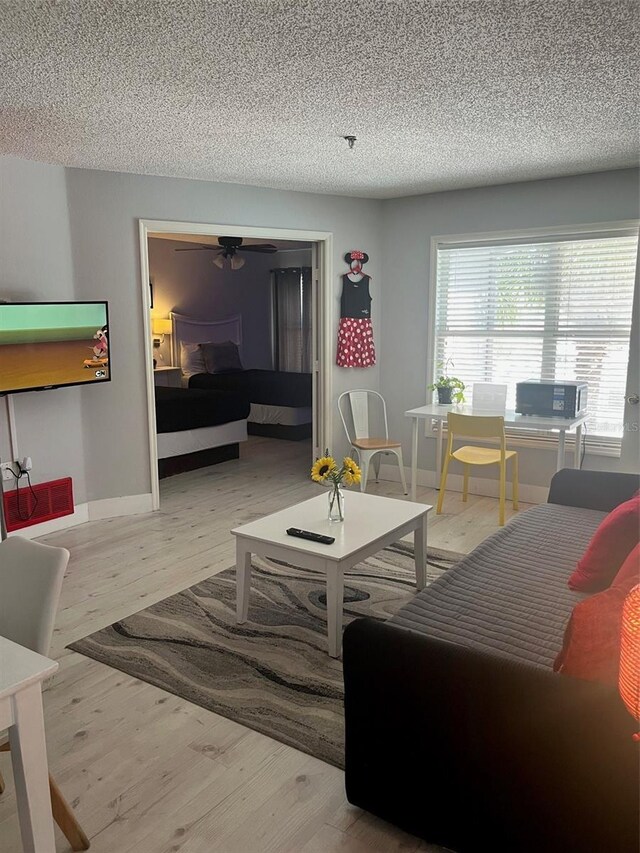 bedroom featuring baseboards, a textured ceiling, and wood finished floors