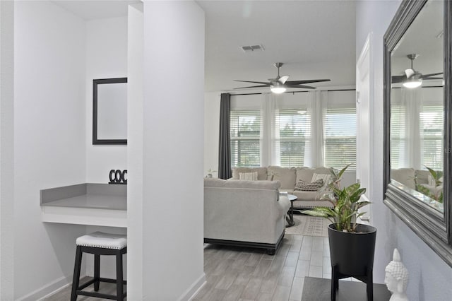 living area featuring wood finished floors, a ceiling fan, visible vents, and baseboards