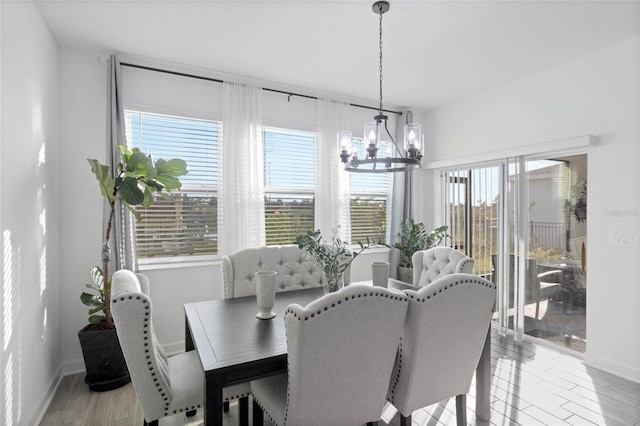 dining room featuring light wood finished floors, a notable chandelier, and baseboards