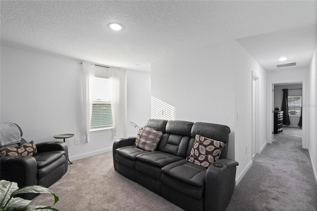 carpeted living area with visible vents, baseboards, and a textured ceiling