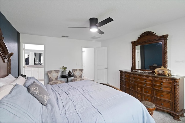 carpeted bedroom with ensuite bath, visible vents, and ceiling fan