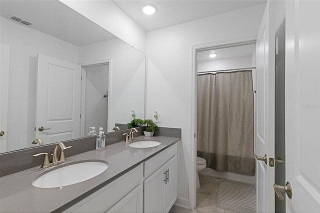 bathroom with double vanity, visible vents, toilet, and a sink