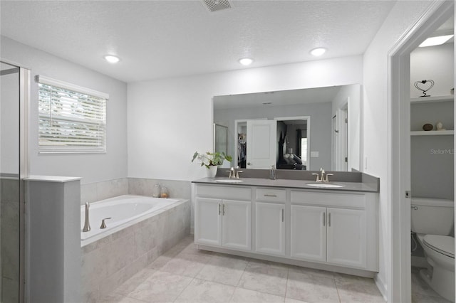 bathroom featuring a bath, double vanity, toilet, and a sink