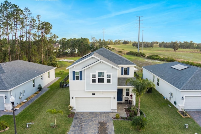 traditional home with a shingled roof, a front lawn, stucco siding, decorative driveway, and an attached garage