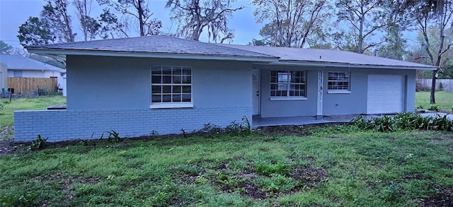 ranch-style home with stucco siding, a front lawn, fence, an attached garage, and brick siding