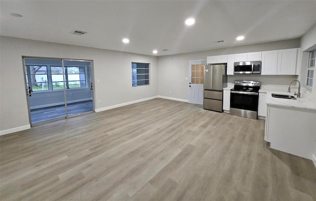 kitchen with light wood finished floors, visible vents, stainless steel appliances, white cabinetry, and a sink