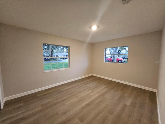 empty room with dark wood-style floors and baseboards