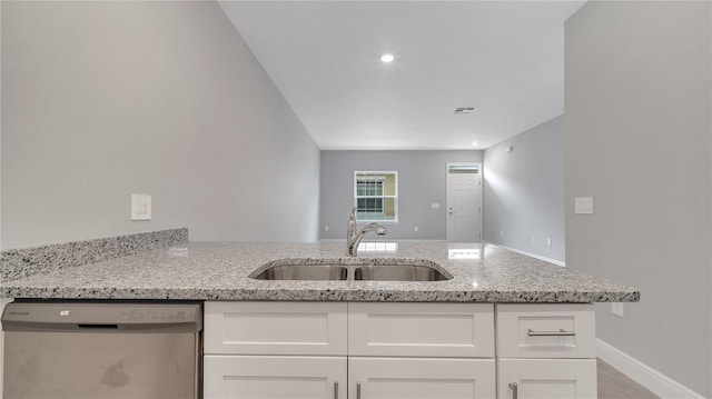 kitchen with light stone countertops, white cabinetry, visible vents, dishwasher, and a sink