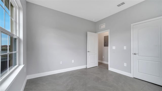 unfurnished bedroom with visible vents, baseboards, tile patterned flooring, and electric panel