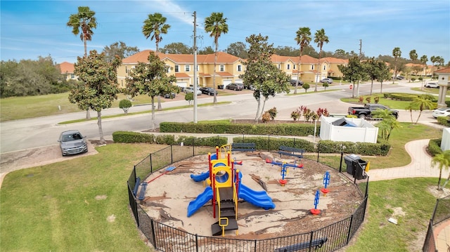 view of property's community featuring a residential view, playground community, fence, and a lawn