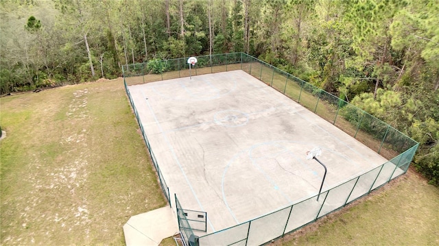 exterior space featuring community basketball court, fence, and a lawn