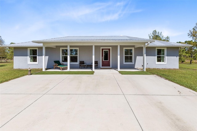 ranch-style home with stucco siding, metal roof, and a front lawn