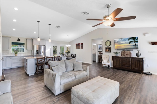 living area featuring baseboards, visible vents, dark wood finished floors, lofted ceiling, and ceiling fan with notable chandelier