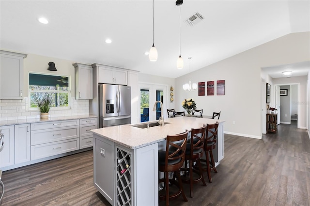 kitchen featuring visible vents, a sink, tasteful backsplash, stainless steel fridge with ice dispenser, and lofted ceiling