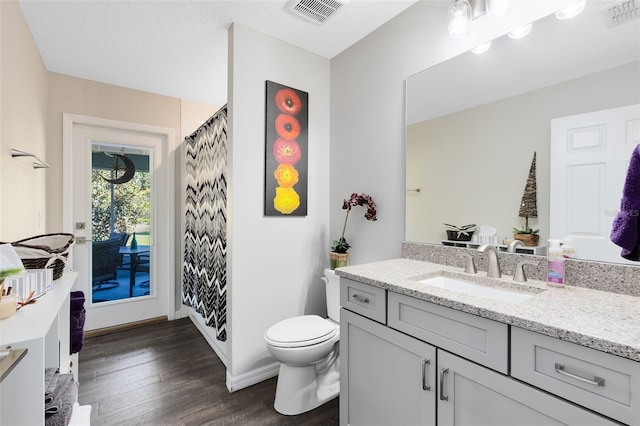 full bathroom featuring vanity, toilet, wood finished floors, and visible vents