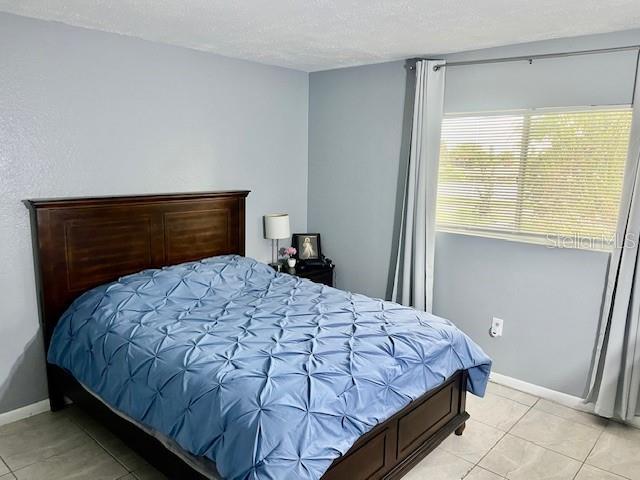 bedroom with light tile patterned floors, baseboards, and a textured ceiling