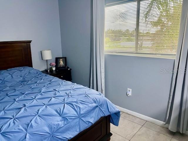 bedroom featuring light tile patterned floors and baseboards