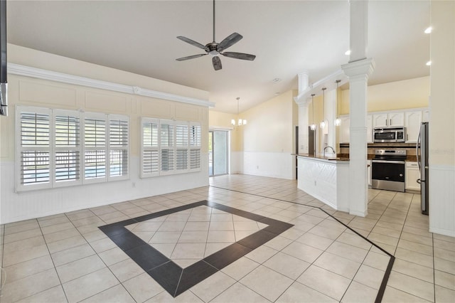 interior space with appliances with stainless steel finishes, light tile patterned flooring, wainscoting, and ceiling fan with notable chandelier