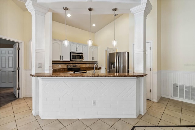 kitchen featuring light tile patterned floors, a wainscoted wall, visible vents, decorative columns, and stainless steel appliances