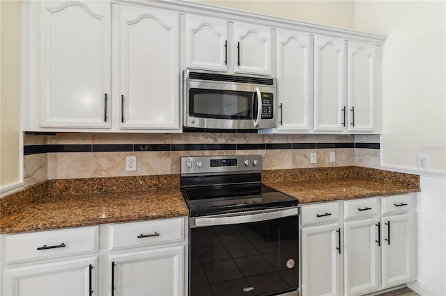 kitchen featuring dark stone counters, appliances with stainless steel finishes, wainscoting, and white cabinetry