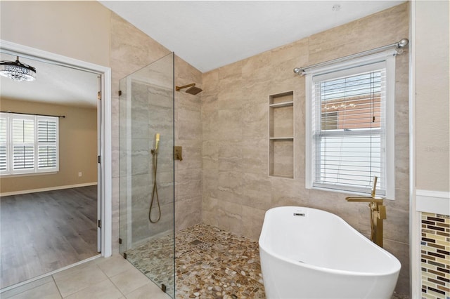 bathroom featuring tile patterned floors, a soaking tub, tile walls, and a walk in shower