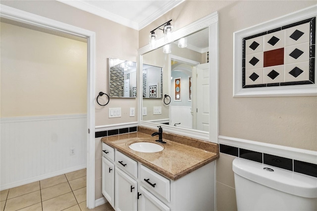 bathroom featuring tile patterned floors, toilet, a wainscoted wall, and ornamental molding