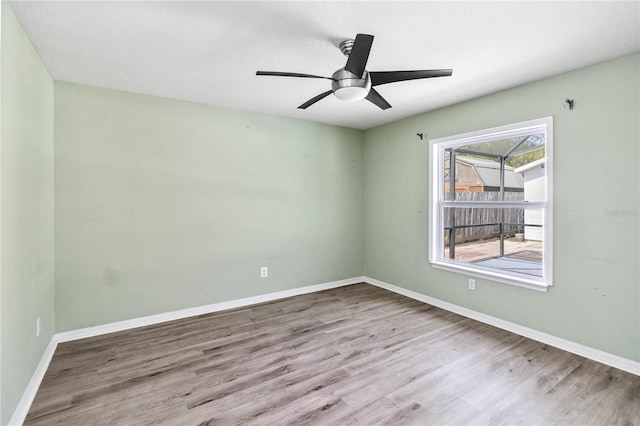 empty room featuring ceiling fan, baseboards, and wood finished floors