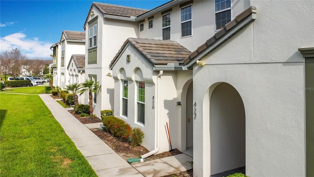 view of home's exterior featuring a tile roof, a yard, a residential view, and stucco siding