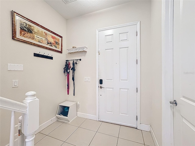 interior space with light tile patterned flooring, visible vents, baseboards, and a textured ceiling