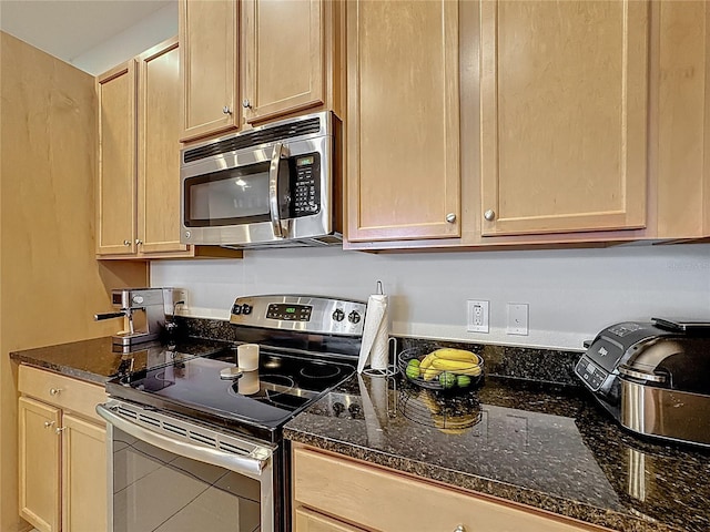 kitchen with dark stone countertops, light brown cabinets, and appliances with stainless steel finishes