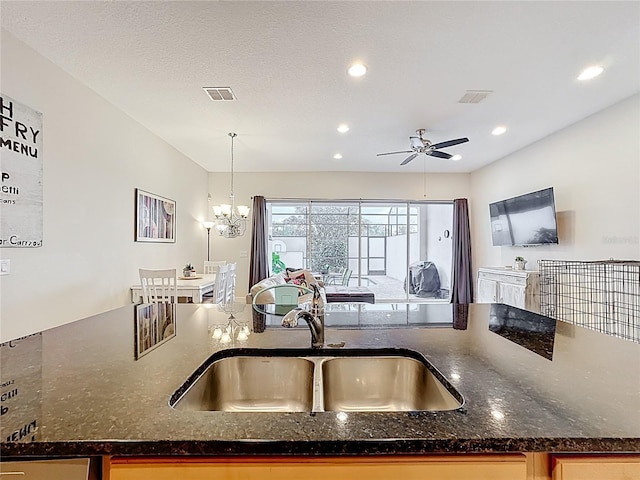 kitchen featuring visible vents, dark stone counters, and a sink