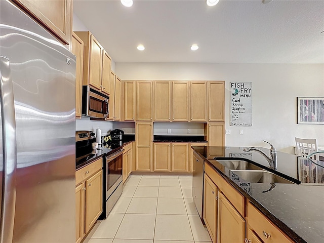 kitchen with dark stone counters, light tile patterned floors, recessed lighting, stainless steel appliances, and a sink