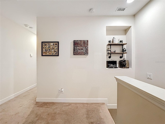 hallway featuring light carpet, visible vents, and baseboards