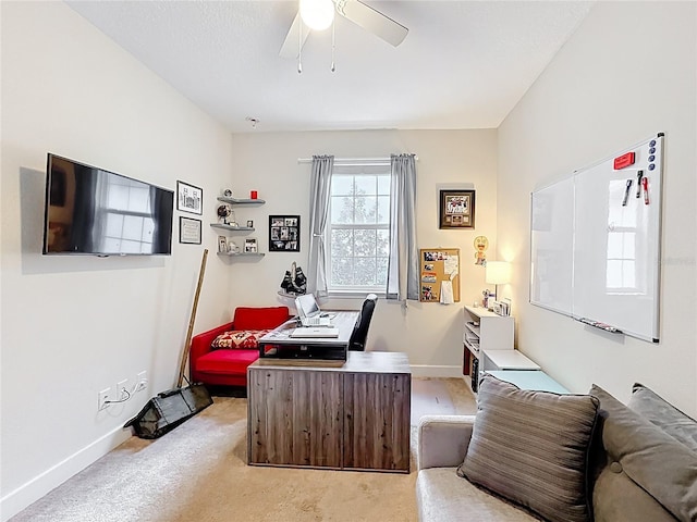 office space with a ceiling fan, light colored carpet, and baseboards