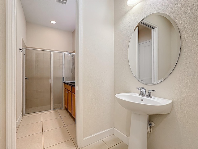 full bathroom with tile patterned floors, baseboards, a shower stall, and a sink