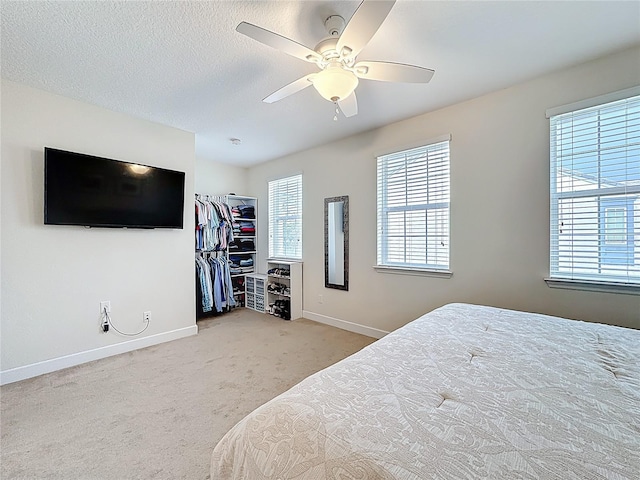 carpeted bedroom with a ceiling fan, baseboards, and a textured ceiling