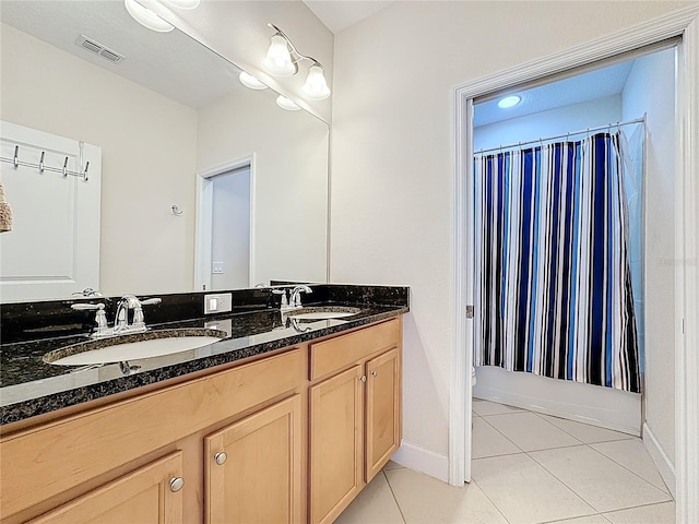 bathroom featuring tile patterned flooring, double vanity, visible vents, and a sink