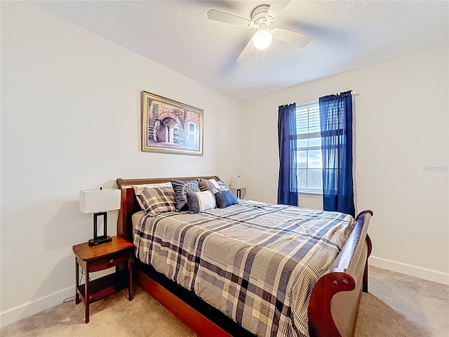 bedroom featuring a ceiling fan, light colored carpet, baseboards, and a textured ceiling