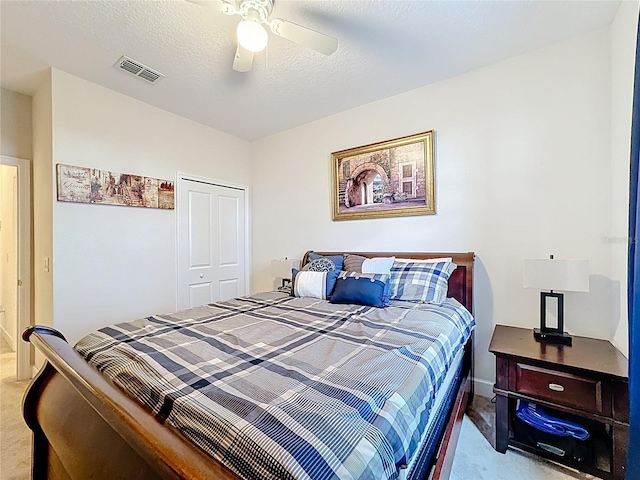 bedroom with ceiling fan, light colored carpet, visible vents, and a textured ceiling