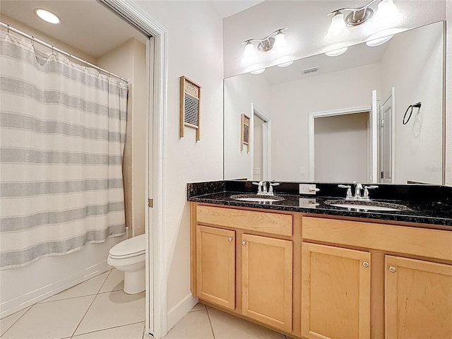 bathroom with tile patterned flooring, double vanity, toilet, and a sink