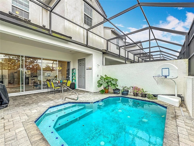 view of swimming pool featuring a patio area and glass enclosure