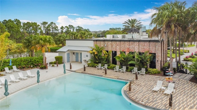 rear view of property with a patio, a community pool, and fence