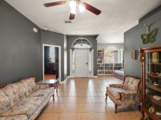 foyer featuring light tile patterned floors, a ceiling fan, baseboards, and a textured ceiling