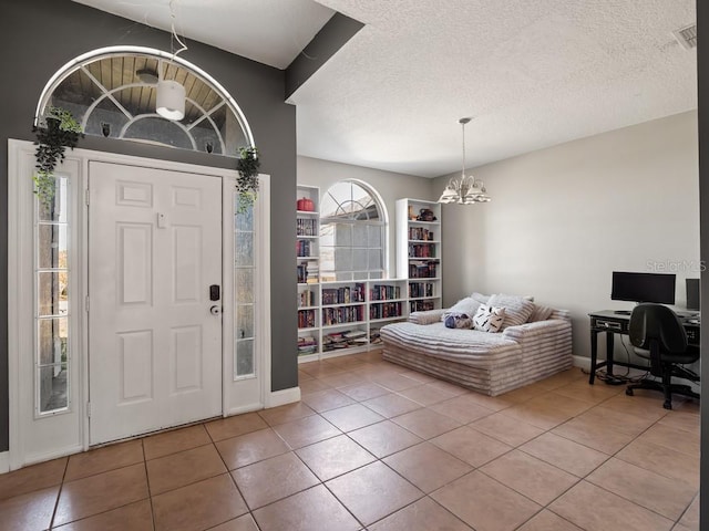 tiled foyer featuring a textured ceiling, visible vents, and a chandelier