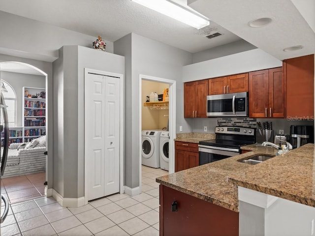 kitchen with light tile patterned floors, visible vents, washing machine and clothes dryer, a sink, and appliances with stainless steel finishes