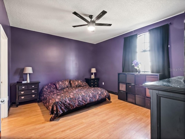 bedroom with light wood-style flooring, a textured ceiling, and ceiling fan