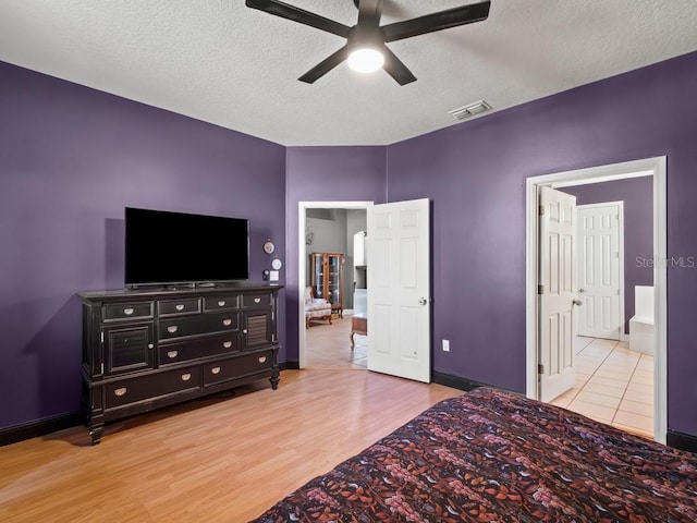 bedroom with wood finished floors, baseboards, visible vents, ceiling fan, and a textured ceiling