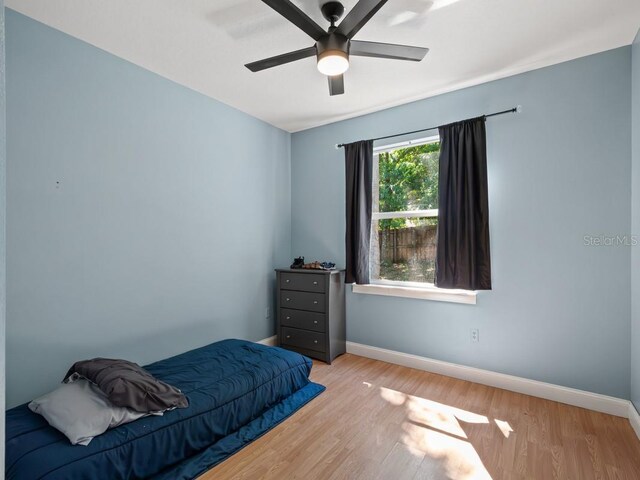 bedroom featuring wood finished floors, baseboards, and ceiling fan