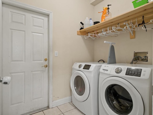 laundry room with laundry area, light tile patterned floors, washing machine and dryer, and baseboards