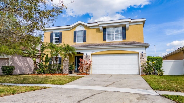 traditional home featuring a front yard, fence, stucco siding, concrete driveway, and a garage